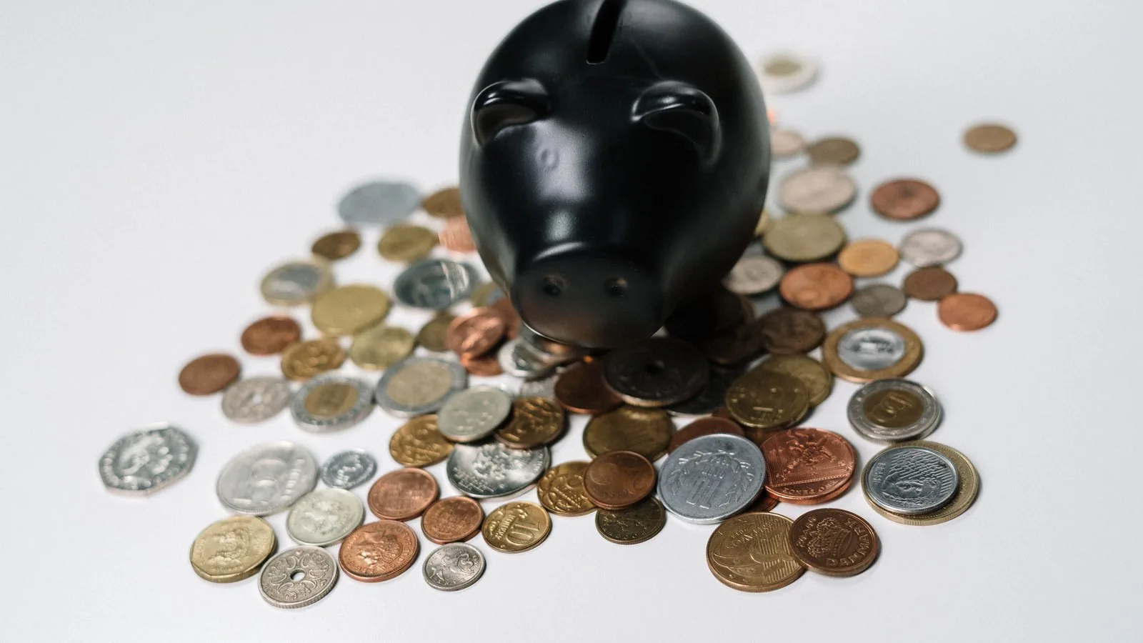 Tirelire noire entourée de pièces de monnaie, illustrant l’épargne de précaution et le rendement réel du Livret A