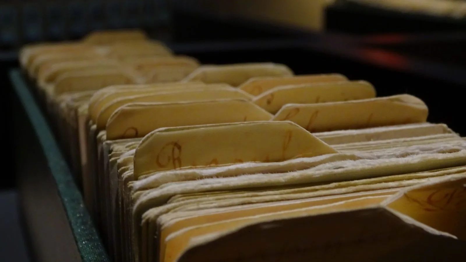 Fiches cartonnées jaunies rangées dans un tiroir d'archives, étiquettes manuscrites