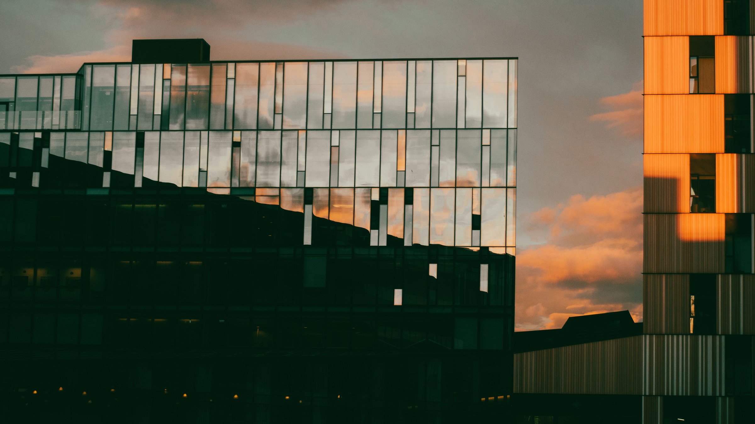 Façade d’un immeuble de bureaux en verre qui reflète le ciel du soir